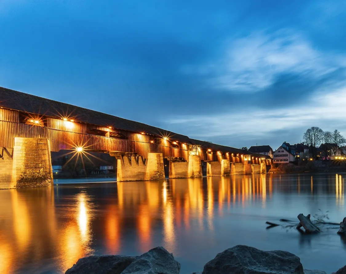 Die beleuchtete Holzbrücke zur blauen Stunde