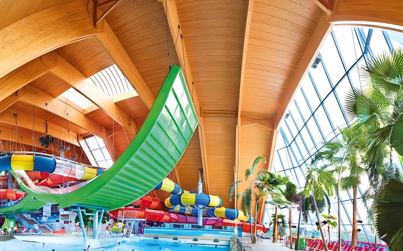Bunte Rutschen und Palmen unter dem Holzdach der Badewelt