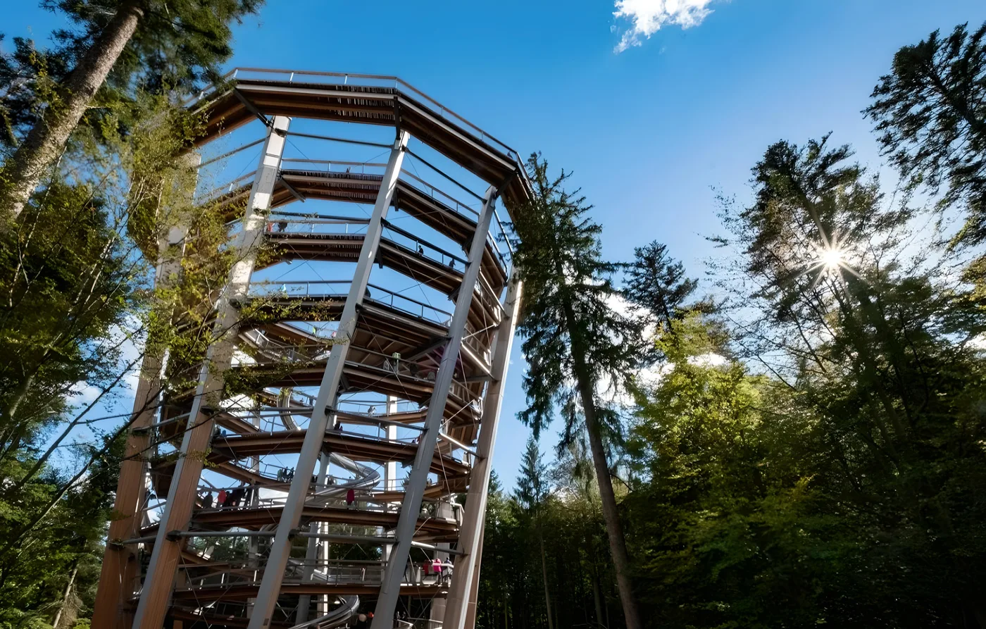 Der geschwungene Holzturm vor blauem Himmel