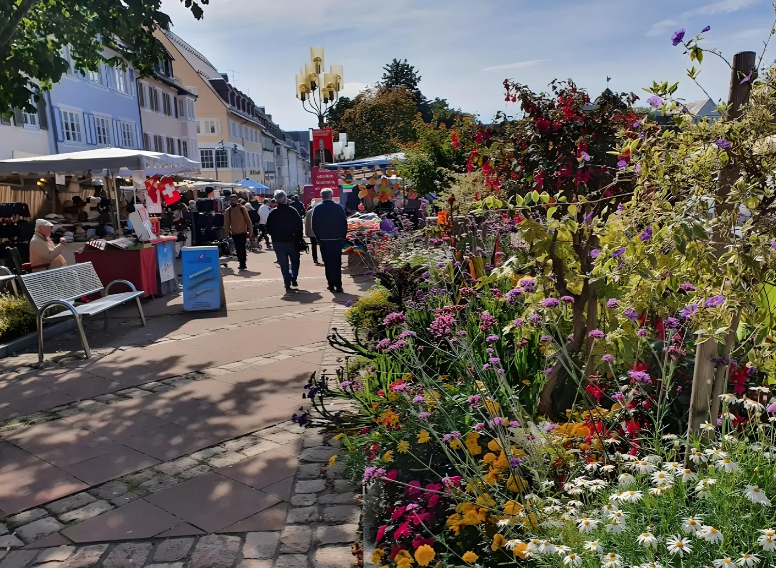 Blühende Beete und Marktstände auf dem Marktplatz