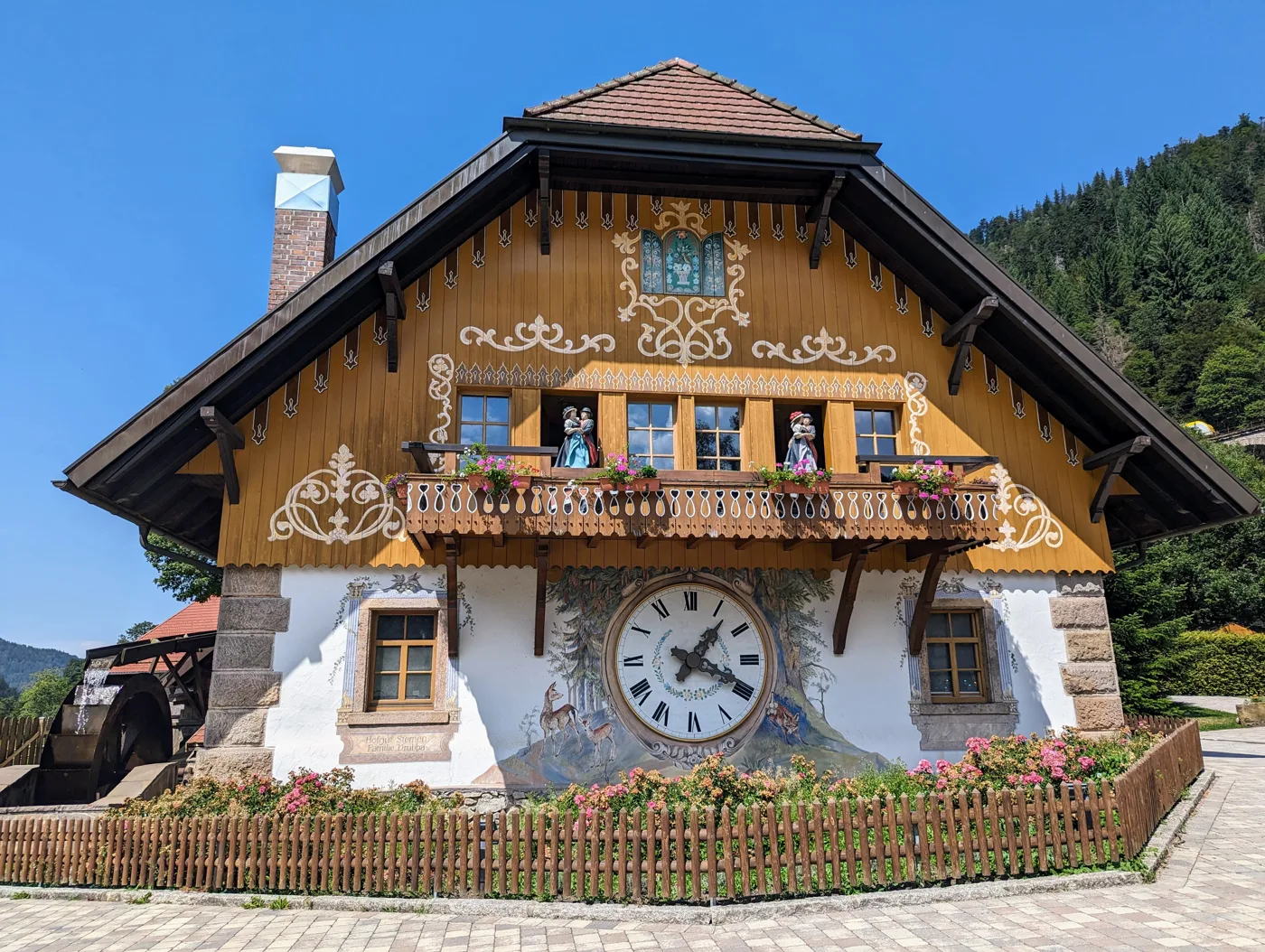 Ein Schwarzwaldhaus mit riesiger Kuckucksuhr am Wegesrand