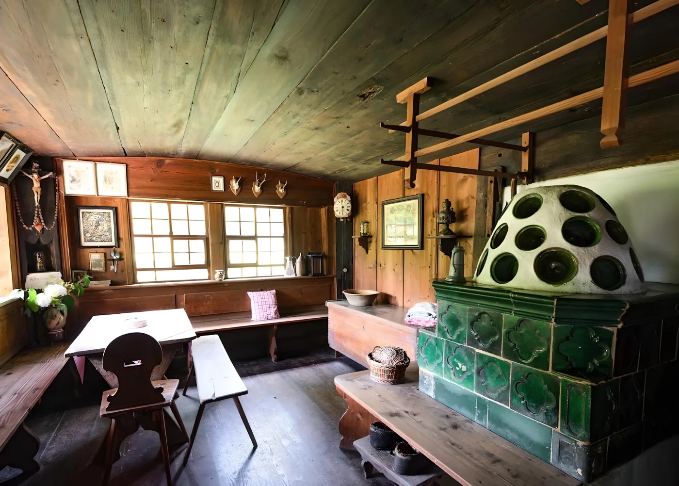 Die Stube mit grünem Kachelofen und langer Tafel