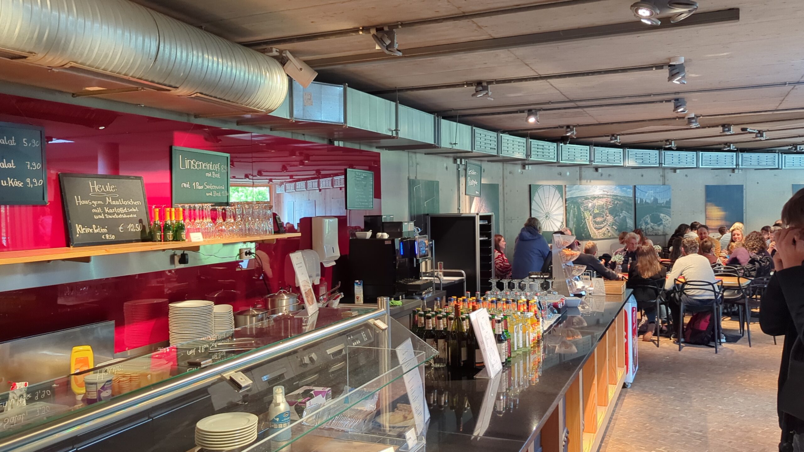 Das Bistro im Gasometer mit roten Sitzmöbeln und Theke.